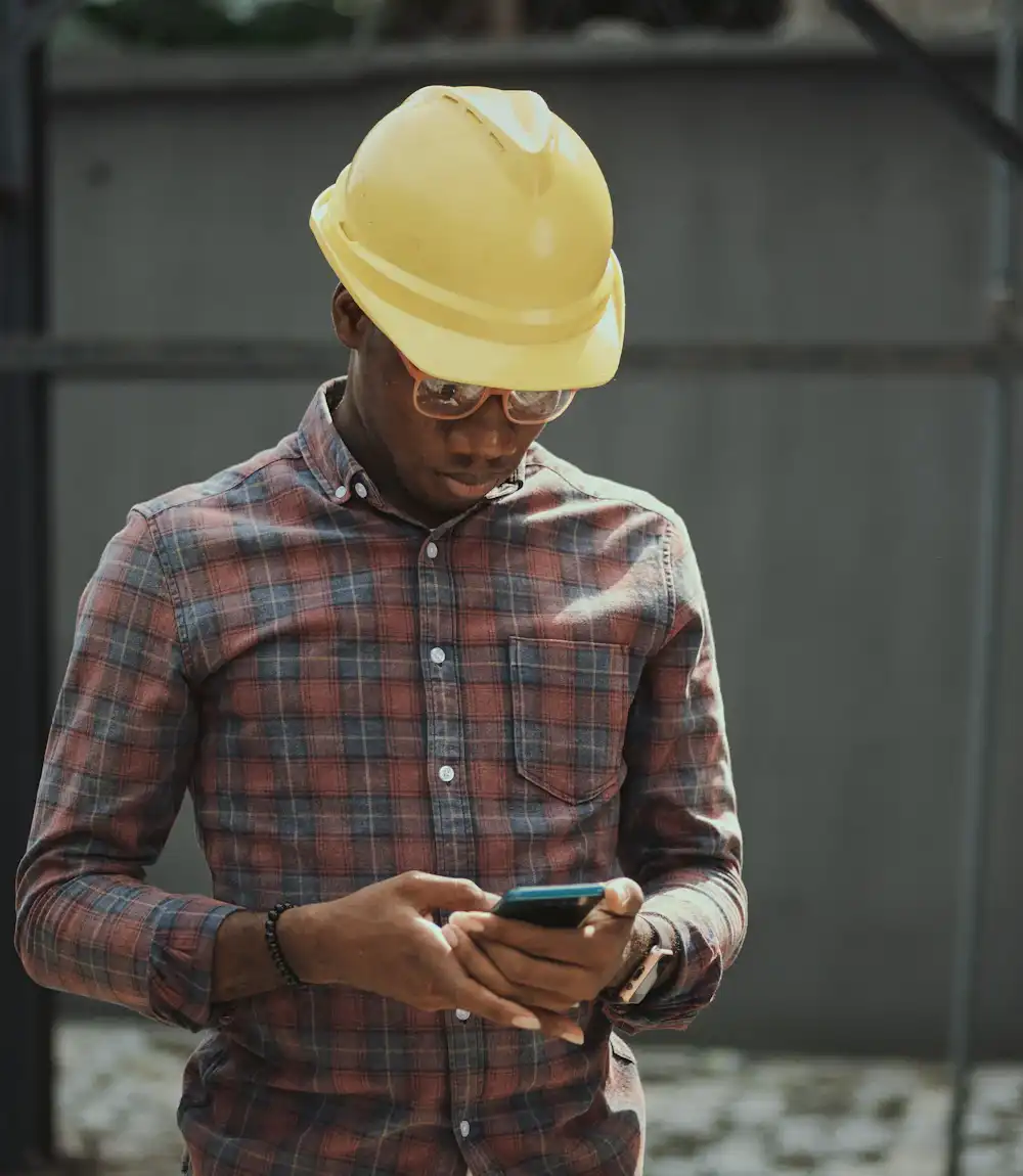 Técnico con casco revisando su orden de trabajo en el celular